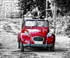 Foto degli sposi sull'auto di nozze