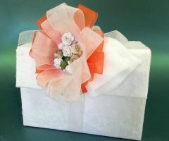 Scatola ricoperta in carta cotone con grande fiocco colorato e fiorellini in carta