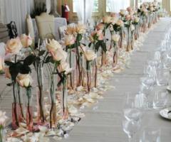 Centrotavola formati da singole rose e da petali sparsi sulla tovaglia