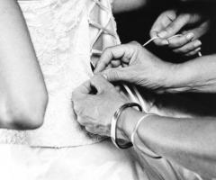 Le sarte aiutano la sposa a chiudere il corpetto dell'abito