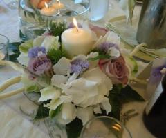 Centrotavola con fiori e candele per i tavoli di matrimonio