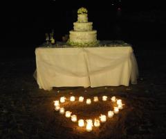Torta nuziale in spiaggia con candele a forma di cuore