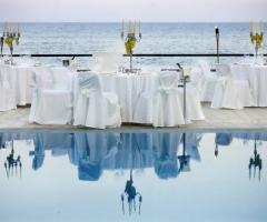 Tavoli apparecchiati a bordo piscina per il ricevimento di matrimonio