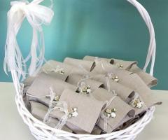 Sacchettini in lino contenenti la bomboniera chiusi da un fiocchetto e un fiorellino in carta