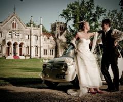 Sposi sulla macchina da cerimonia all'entrata del castello