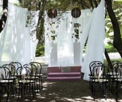 Allestimento floreale con stoffe bianche per la cerimonia in giardino