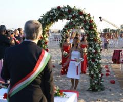 Sposarsi sulla spiaggia sotto un arco di fiori