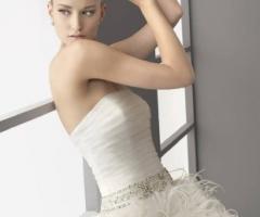 Abito da sposa con cinta preziosa e piume applicate sulla gonna