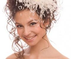 Acconciatura raccolta con grande fermaglio di piume e trucco arancio